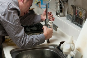 Picture of a man working on a sink.